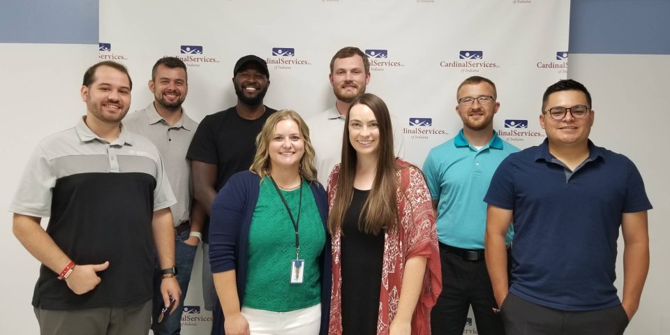 Iindividuals from the Young Adult Professionals stop to pose in front of the Cardinal banner during their Changing Lives Tour