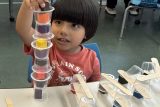 photo of a small boy bui;ding a tower of plastic blocks