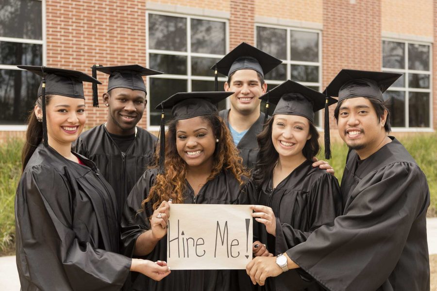 alt=a group of young graduates hold a sign saying hire me