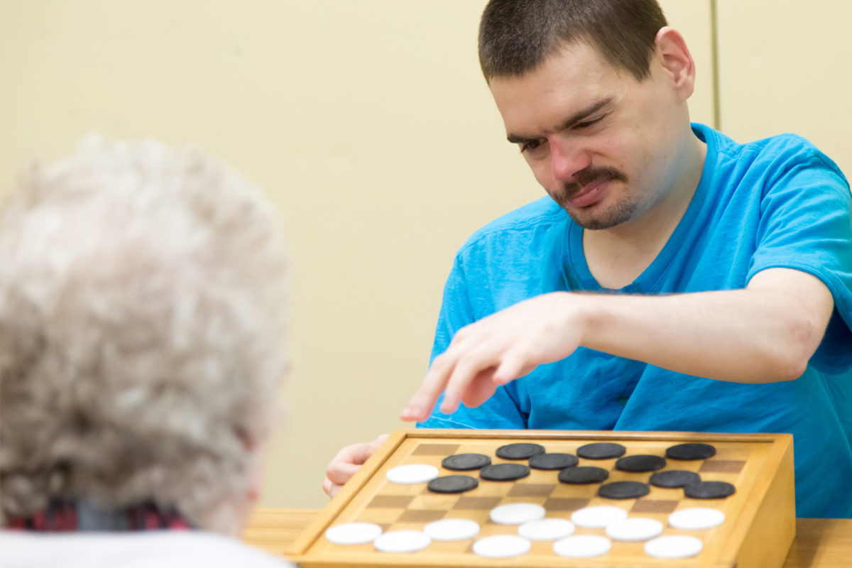 Man wearing blue shirt playing checkers